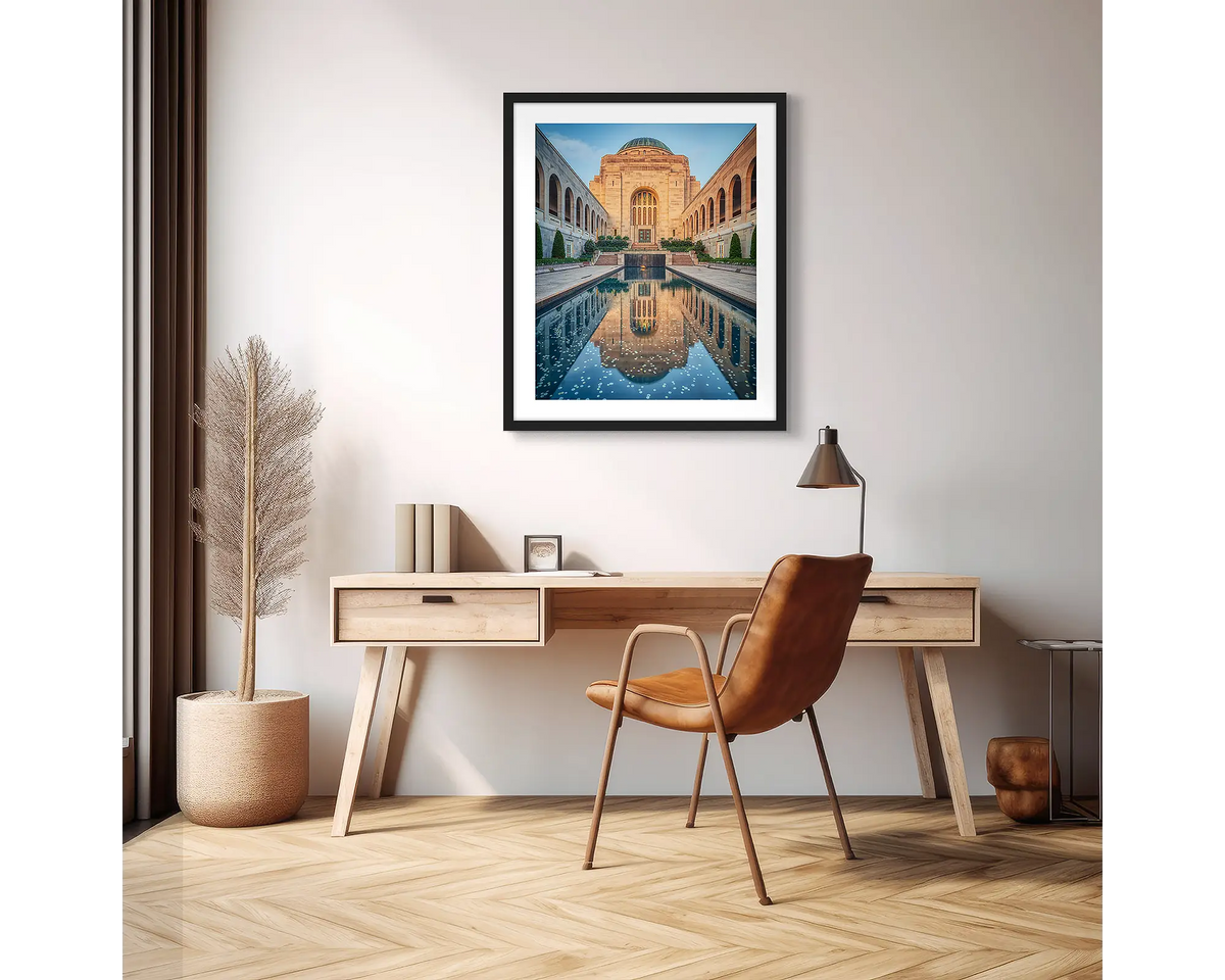 Pool of Reflection. Wall art print of the Australian War Memorial, framed with a black frame and hung above a desk, in an apartment. 