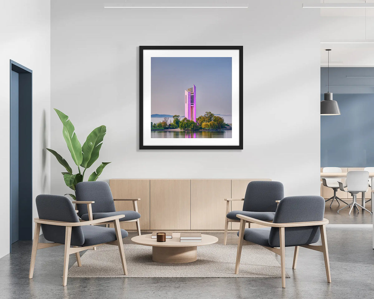 Purple Popsicle. Framed wall art print of the National Carillon, lit up purple, with a black frame in a bright office lobby. 