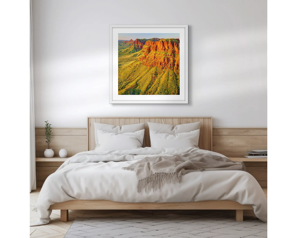 Ragged Bluff. Wall art print of a sunset over east Kimberley, with a white frame hung above a bed. 
