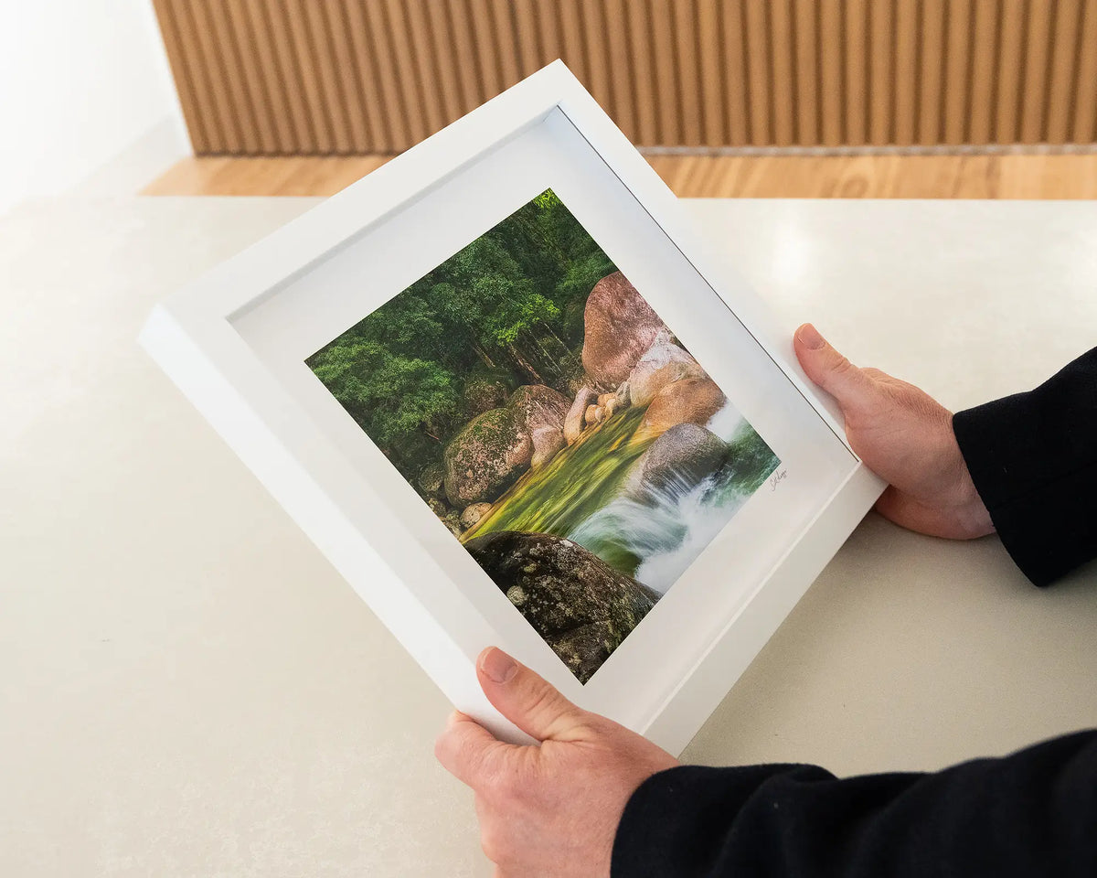 Rainforest Rocks. Mossman Gorge small framed print with white frame being hand held.