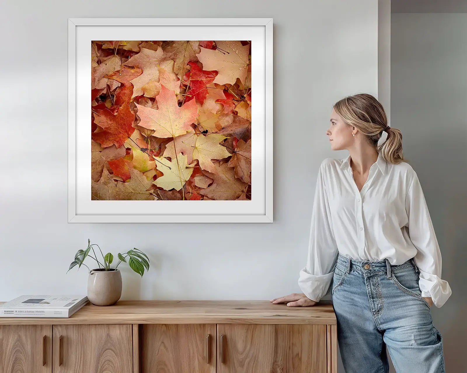 Red autumn leaves wall art print hung above side table.