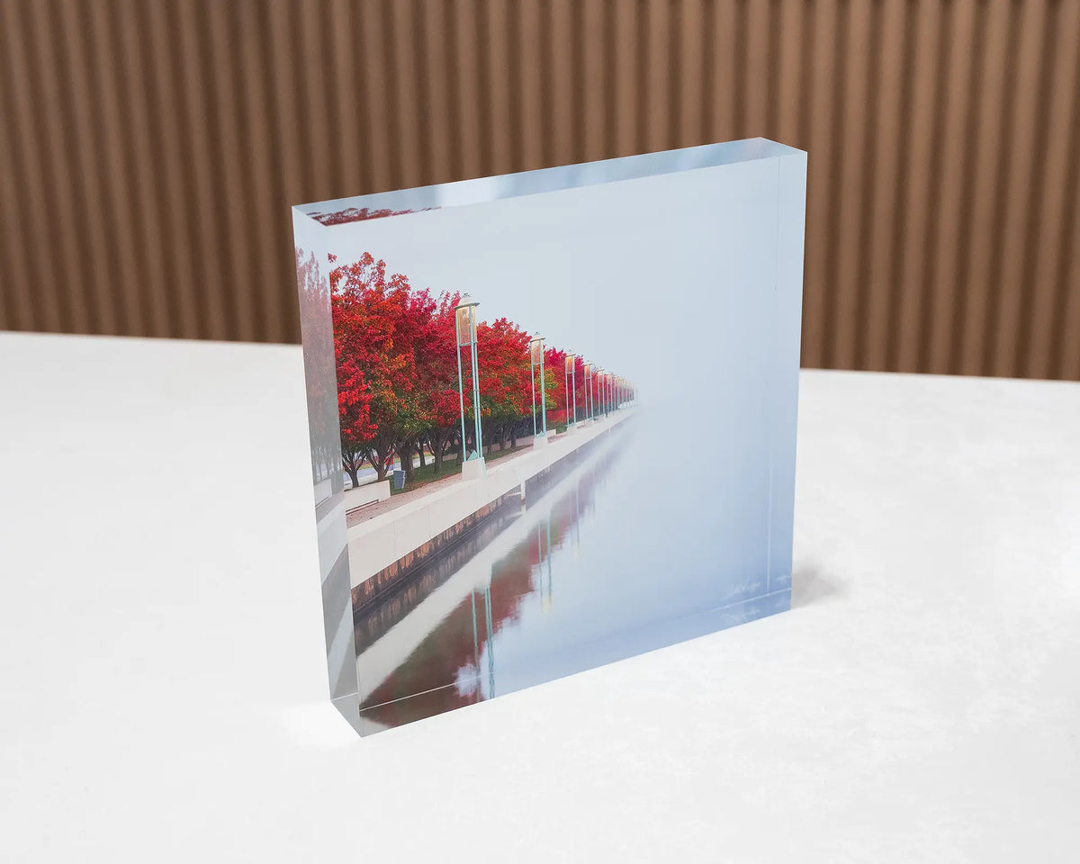 Red Serenity. Acrylic block of autumn trees lining Lake Burley Griffin, Canberra, sitting on a desk.