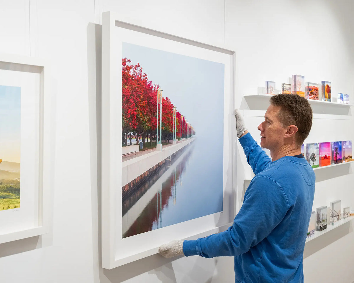 Red Serenity. Fog at Lake Burley Griffin, Canberra, with white frame, being hung on gallery wall.
