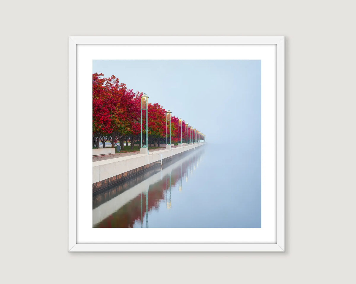 Framed landscape photograph of red autumn trees on a misty lake.