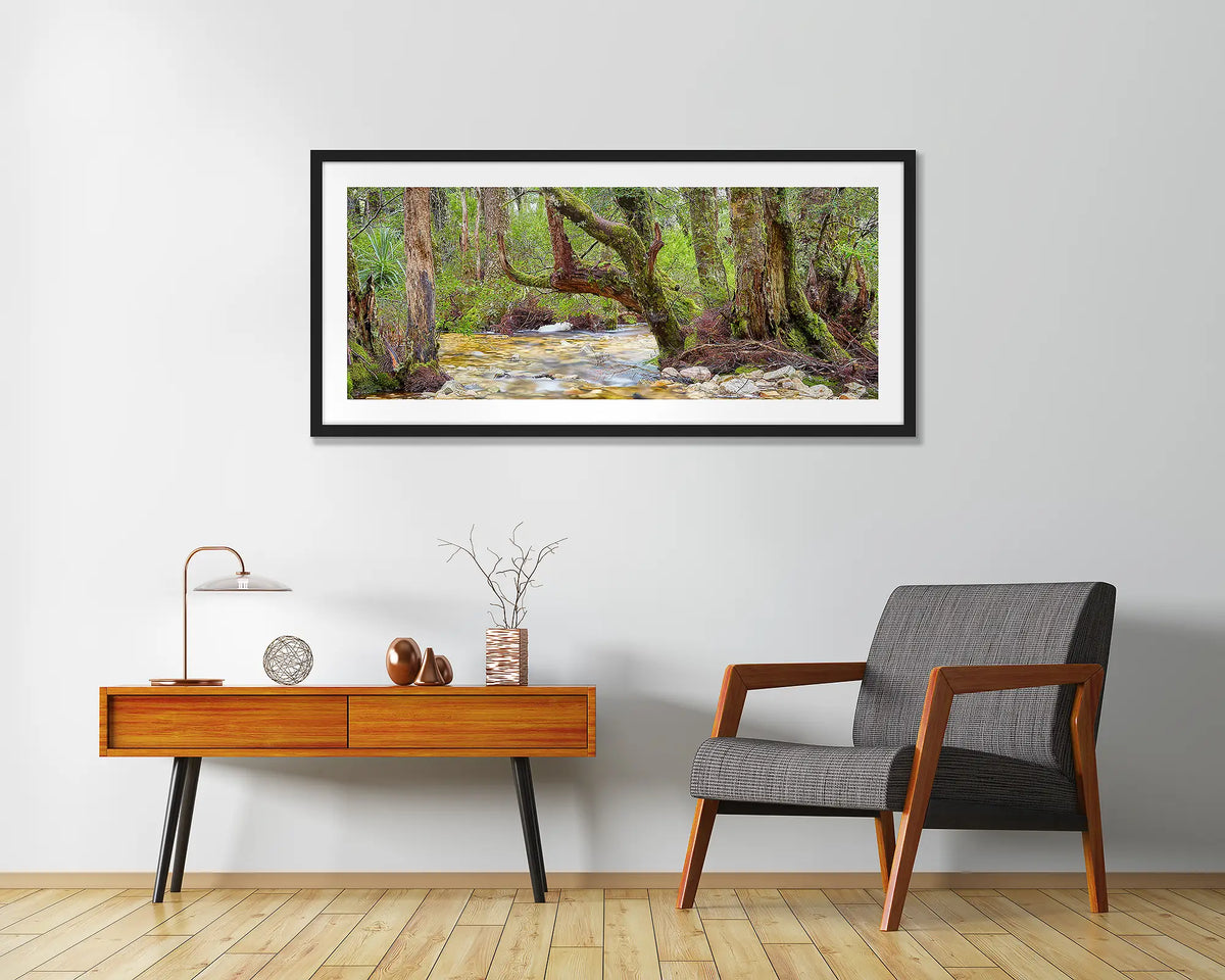 Reverie. Cradle Mountain Lake St Clair wall art print framed with a black frame, hung above a chair and side table. 