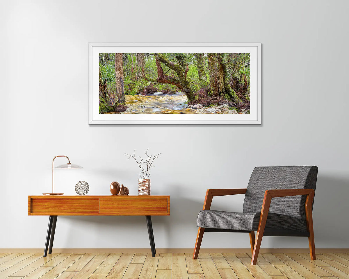 Reverie. Cradle Mountain Lake St Clair wall art print framed with a white frame, hung above a chair and side table. 