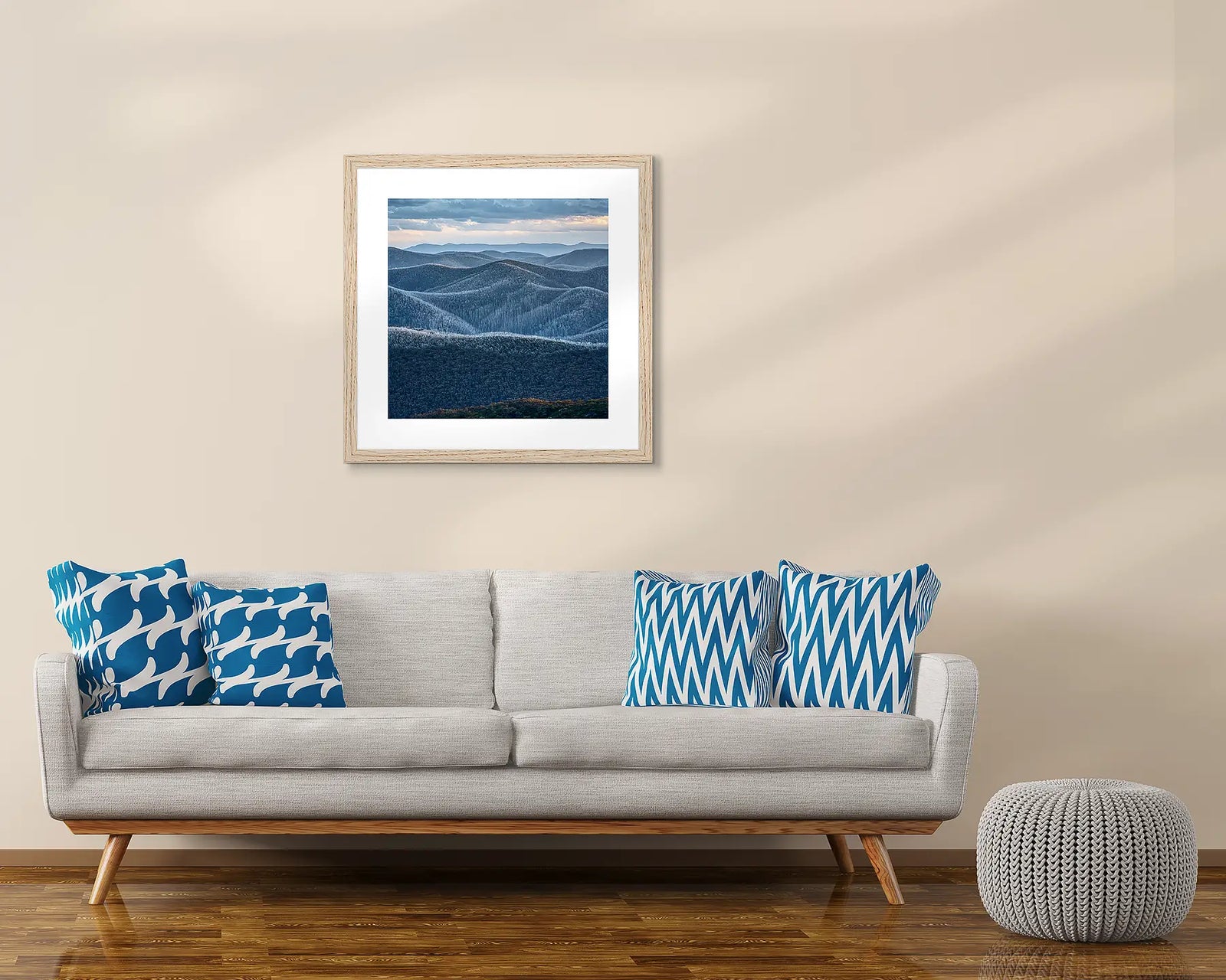 Framed neutral photograph of a mountainous region with forest and a blue grey cloudy sky in Alpine National Park.