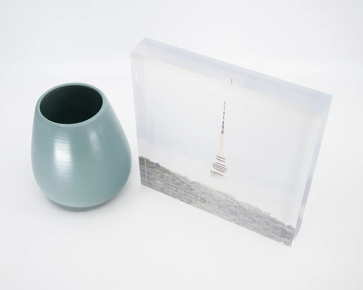 Rising. Acrylic block of Black Mountain Tower in fog, Canberra, on desk with small vase.