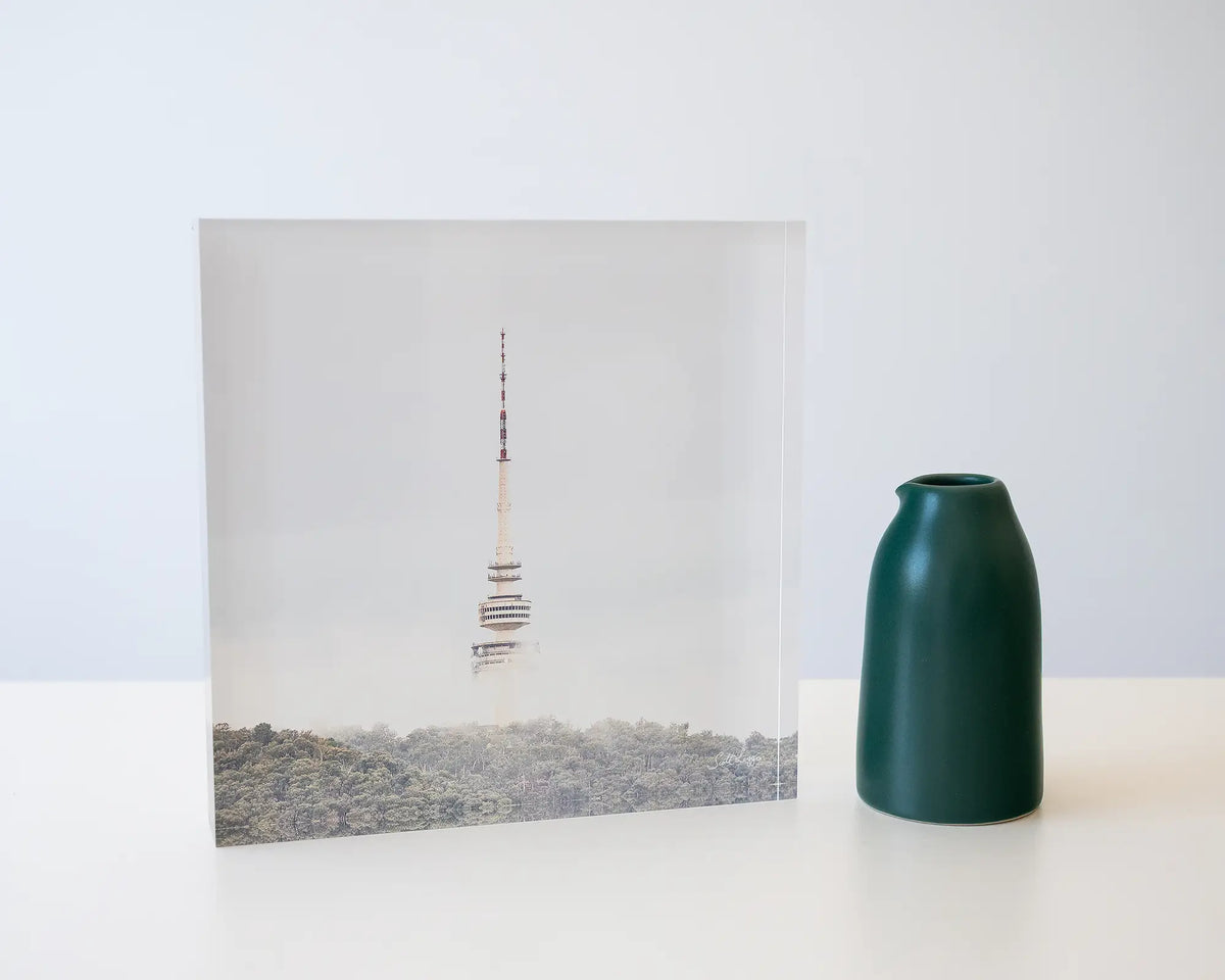 Rising. Acrylic block of Black Mountain Tower in fog, Canberra, styled with a small vase.
