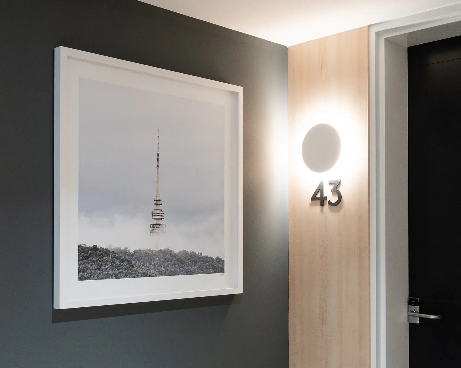 Framed photograph of Telstra Tower in fog with green trees and light blue sky.