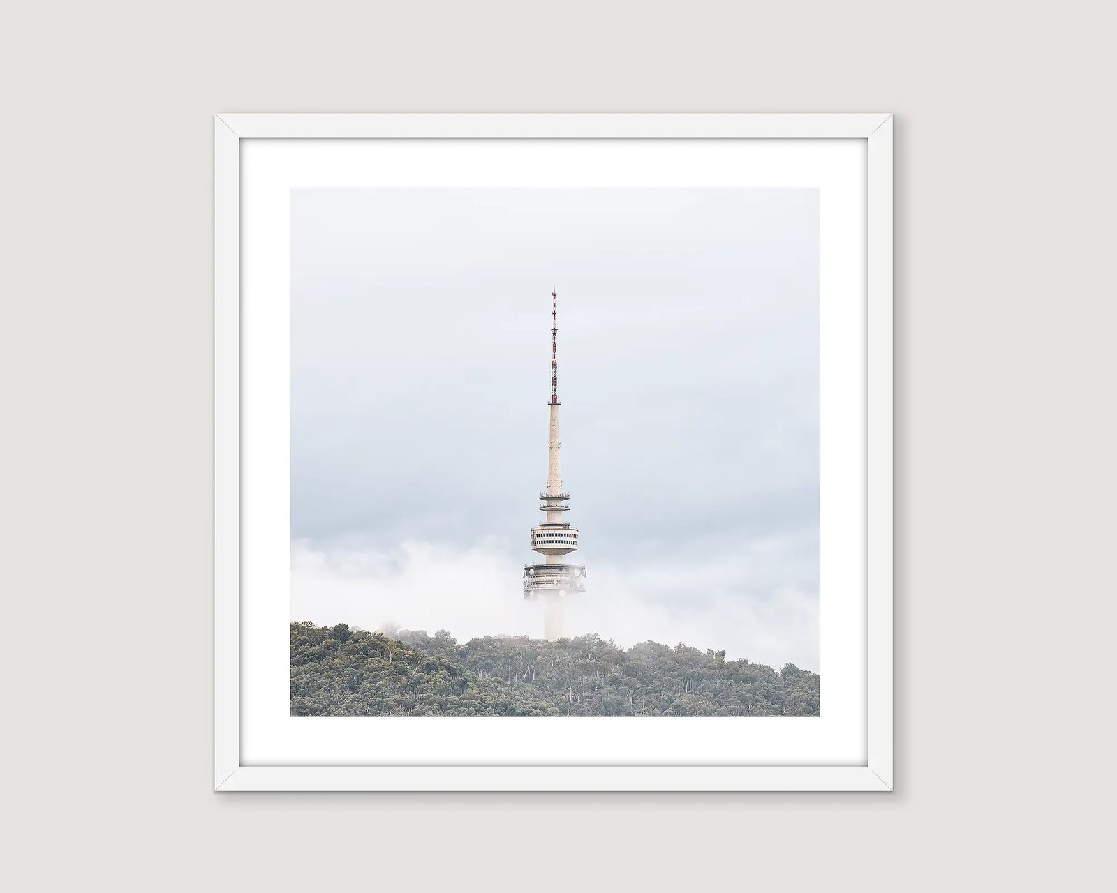 Framed photograph of Telstra Tower in fog with green trees and light blue sky.