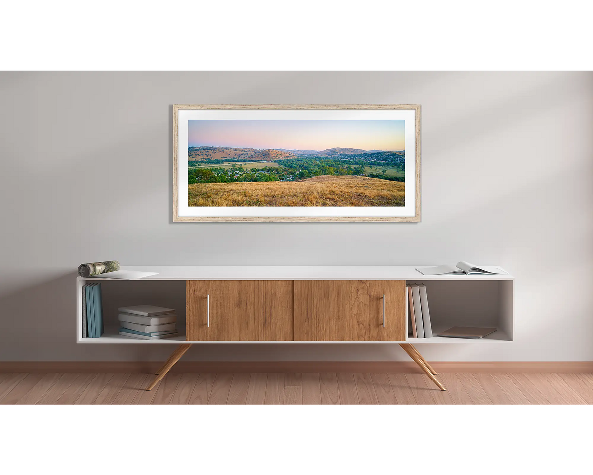 Road to Gundagai. Wall art print with a timber frame, of a sunrise over the town of Gundagai, hung above a side table. 