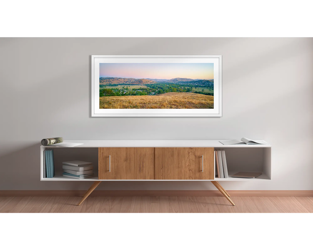 Road to Gundagai. Wall art print with a white frame, of a sunrise over the town of Gundagai, hung above a side table. 