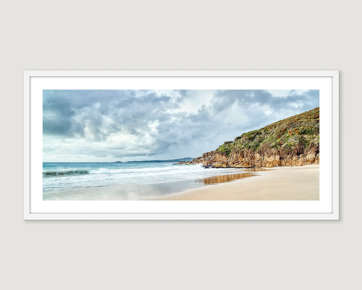 Framed artwork of a beach scene at Zenith Beach with a rocky cliff and cloudy sky.