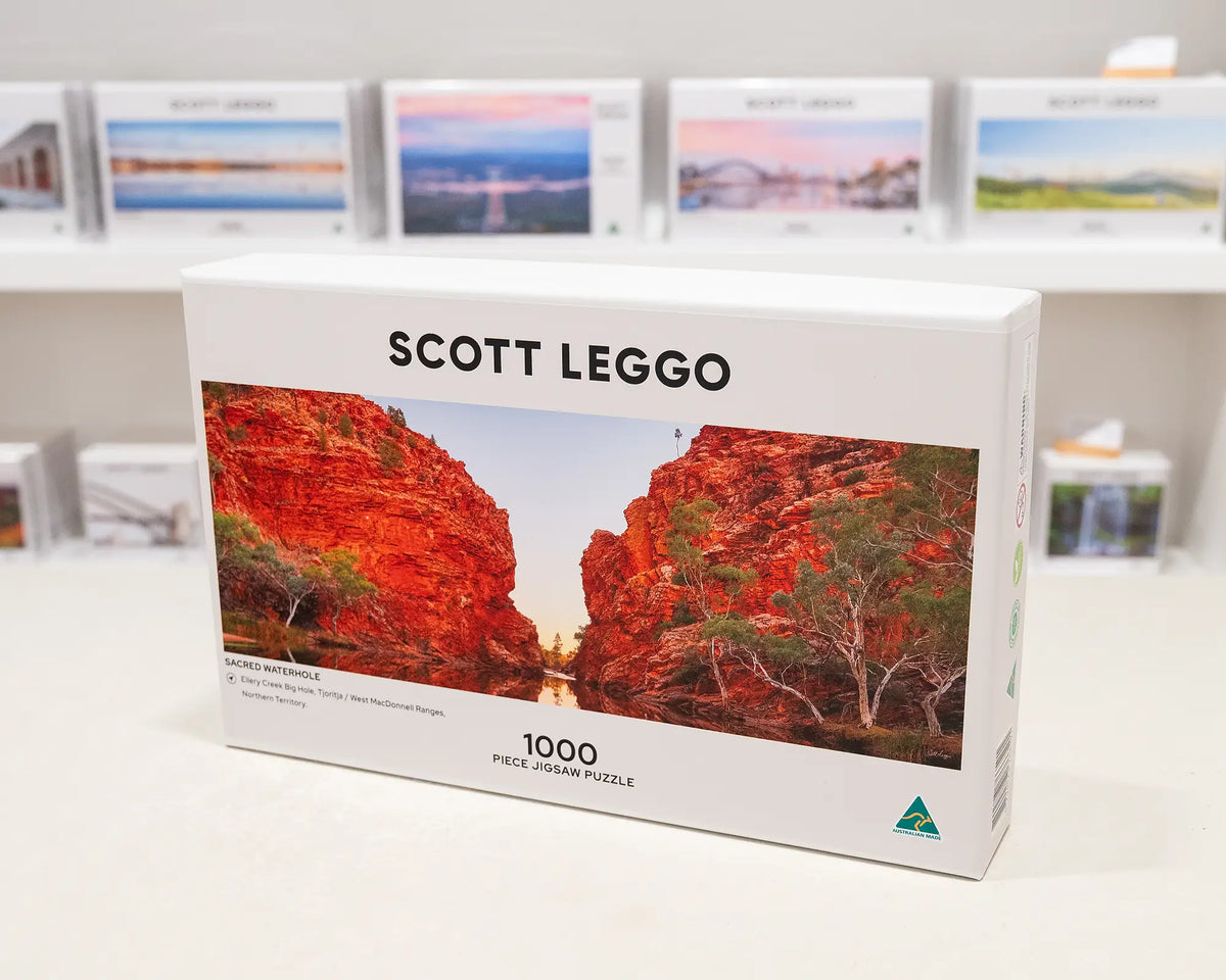 Sacred Waterhole. 1000 piece jigsaw puzzle, West MacDonnell Ranges, Northern Territory, on gallery desk with more puzzles in background.