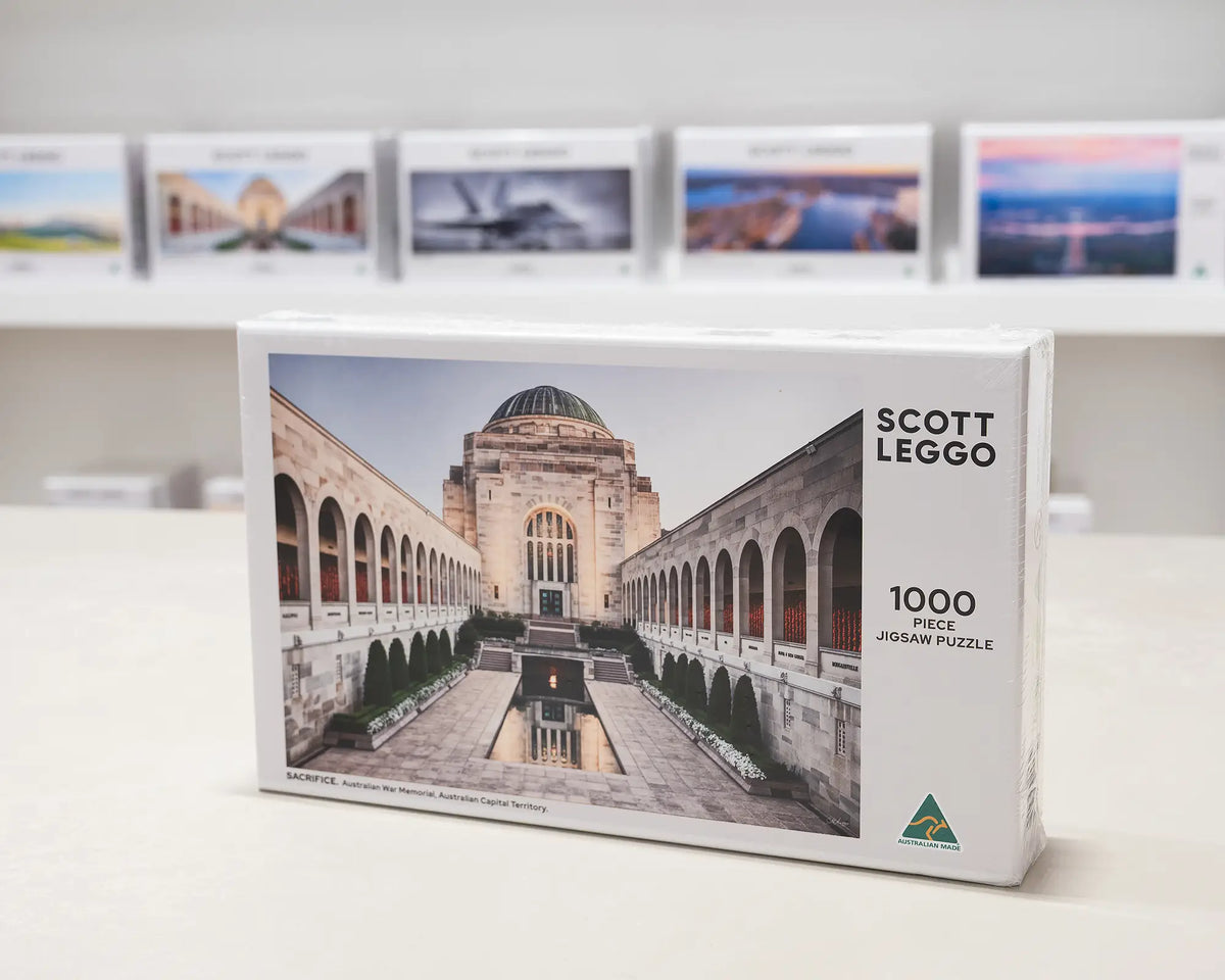 Sacrifice 1000 piece War Memorial jigsaw puzzle box sitting on table in front of other puzzle boxes.