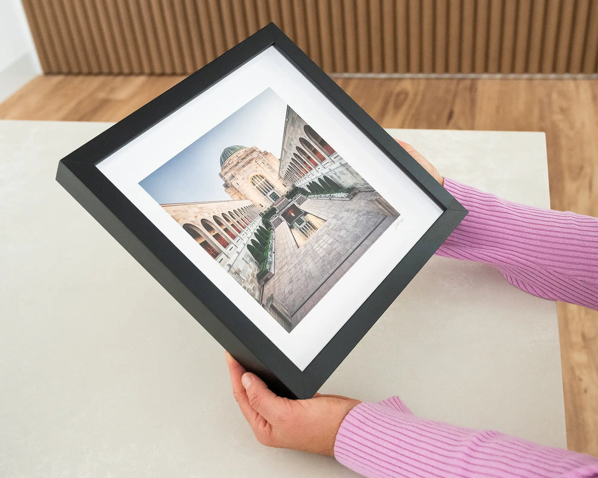 Sacrifice. Small print of the Australian War Memorial with black frame, held in hands.