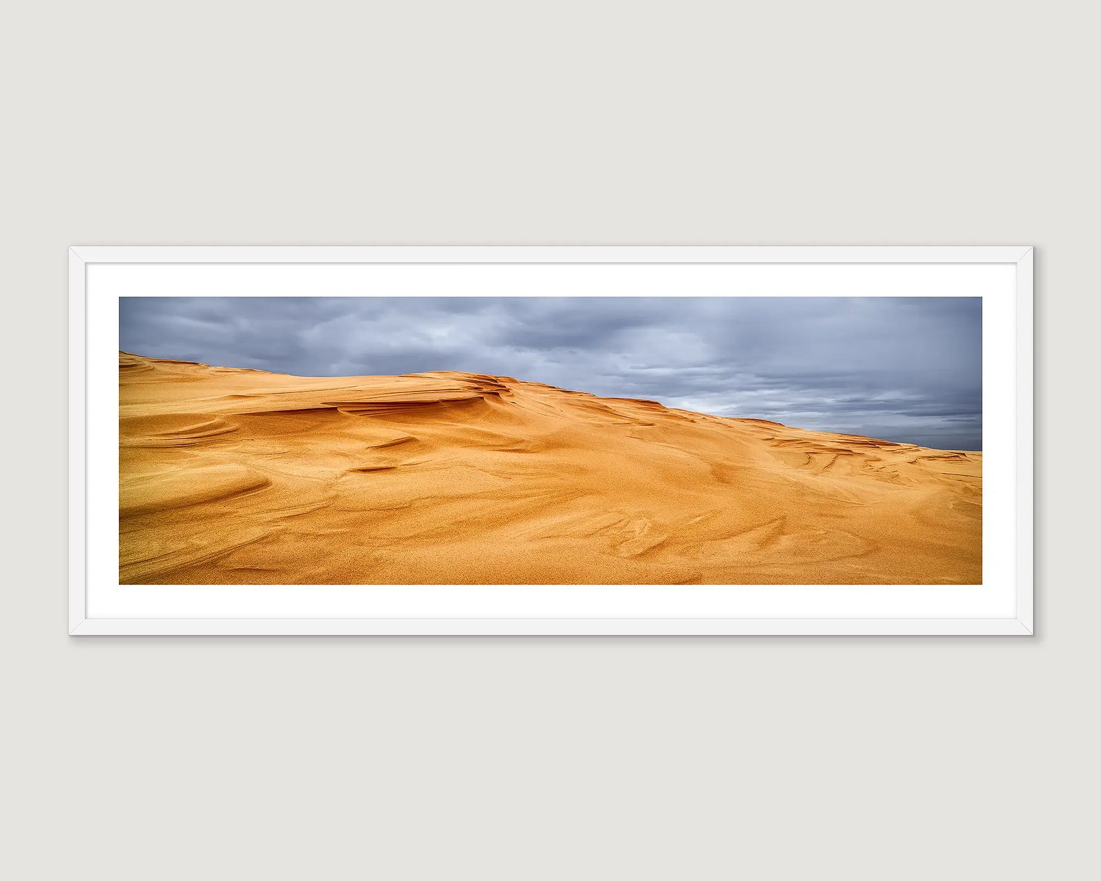 Framed artwork of sand dunes at Stockton Beach with a cloudy sky.