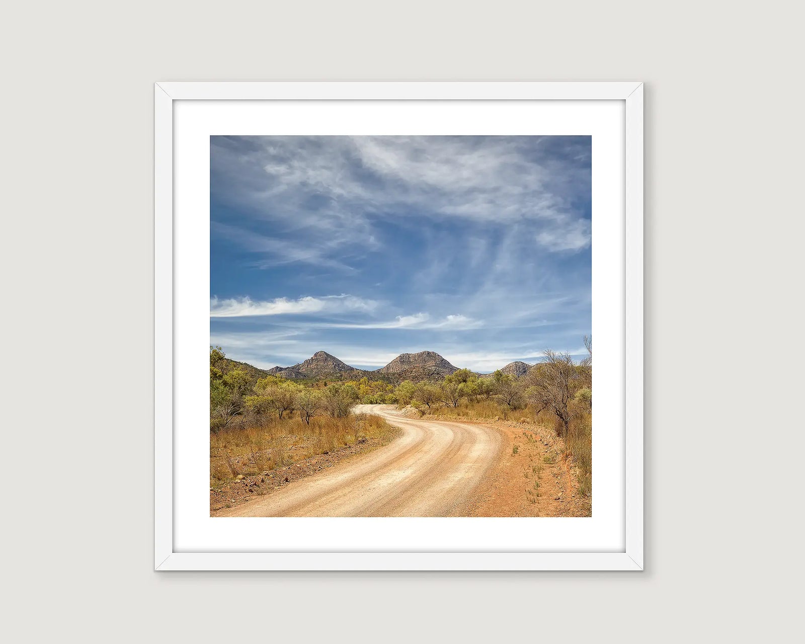 Framed print of a scenic dirt road with mountains and blue sky.