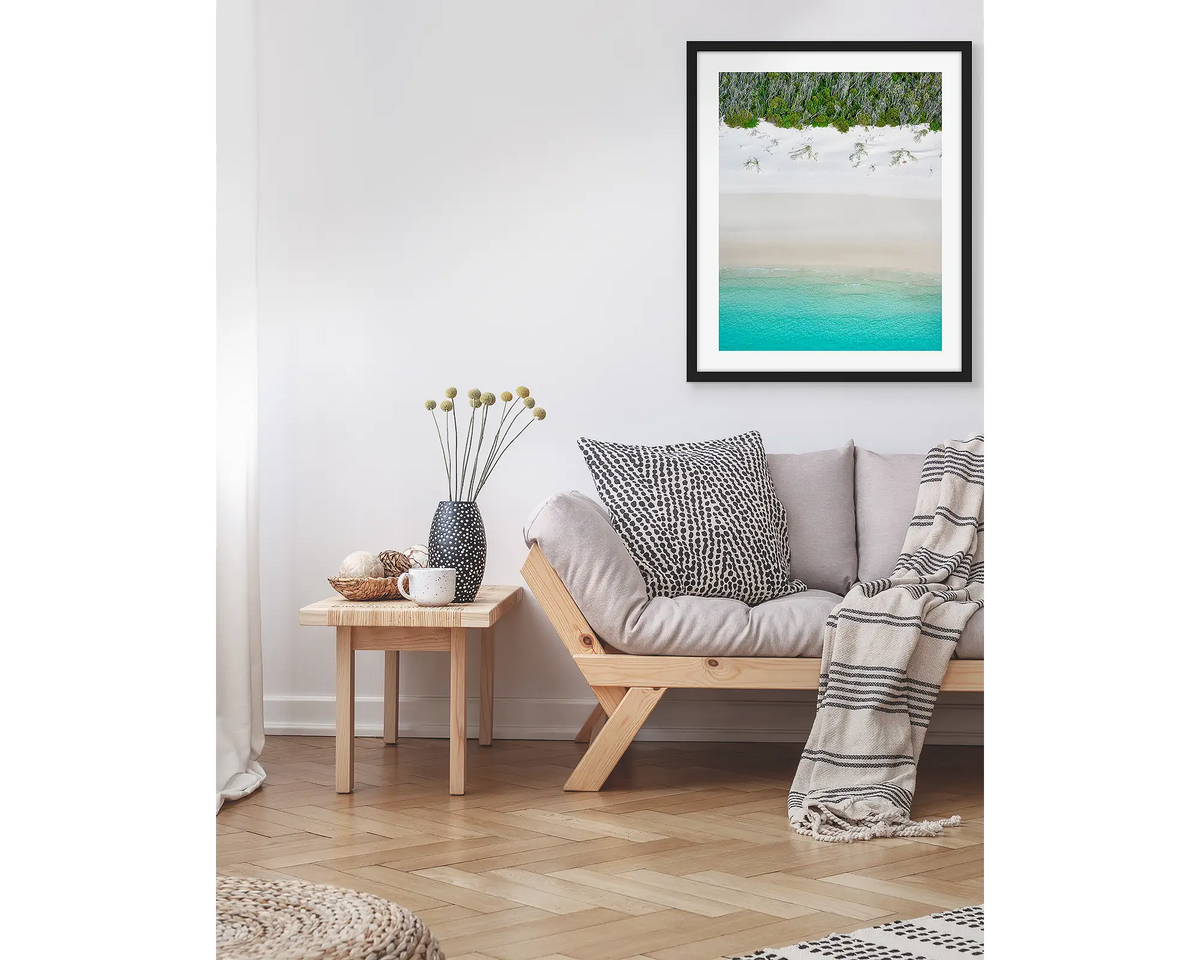 Sea Change. Abstract coastal wall art print, in a black frame, hanging above a couch.