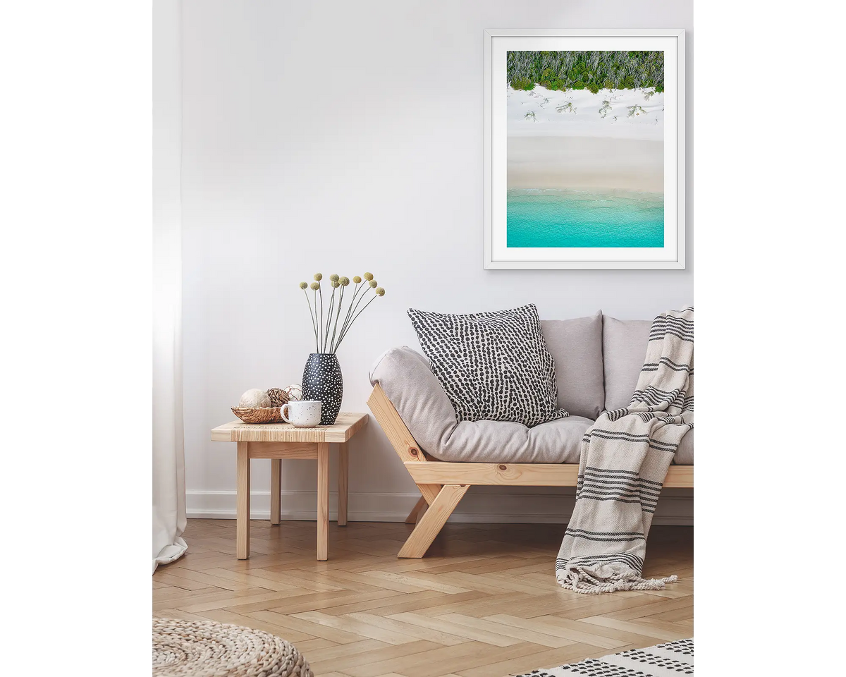 Sea Change. Abstract coastal wall art print, in a white frame, hanging above a couch.
