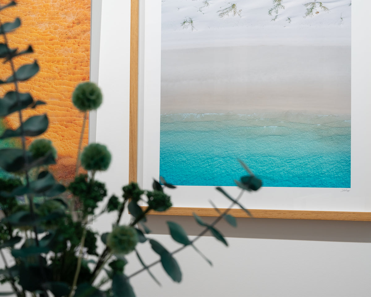 Sea Change. Aerial view Whitehaven Beach, Queensland, with timber frame, close-up with natives in foreground.