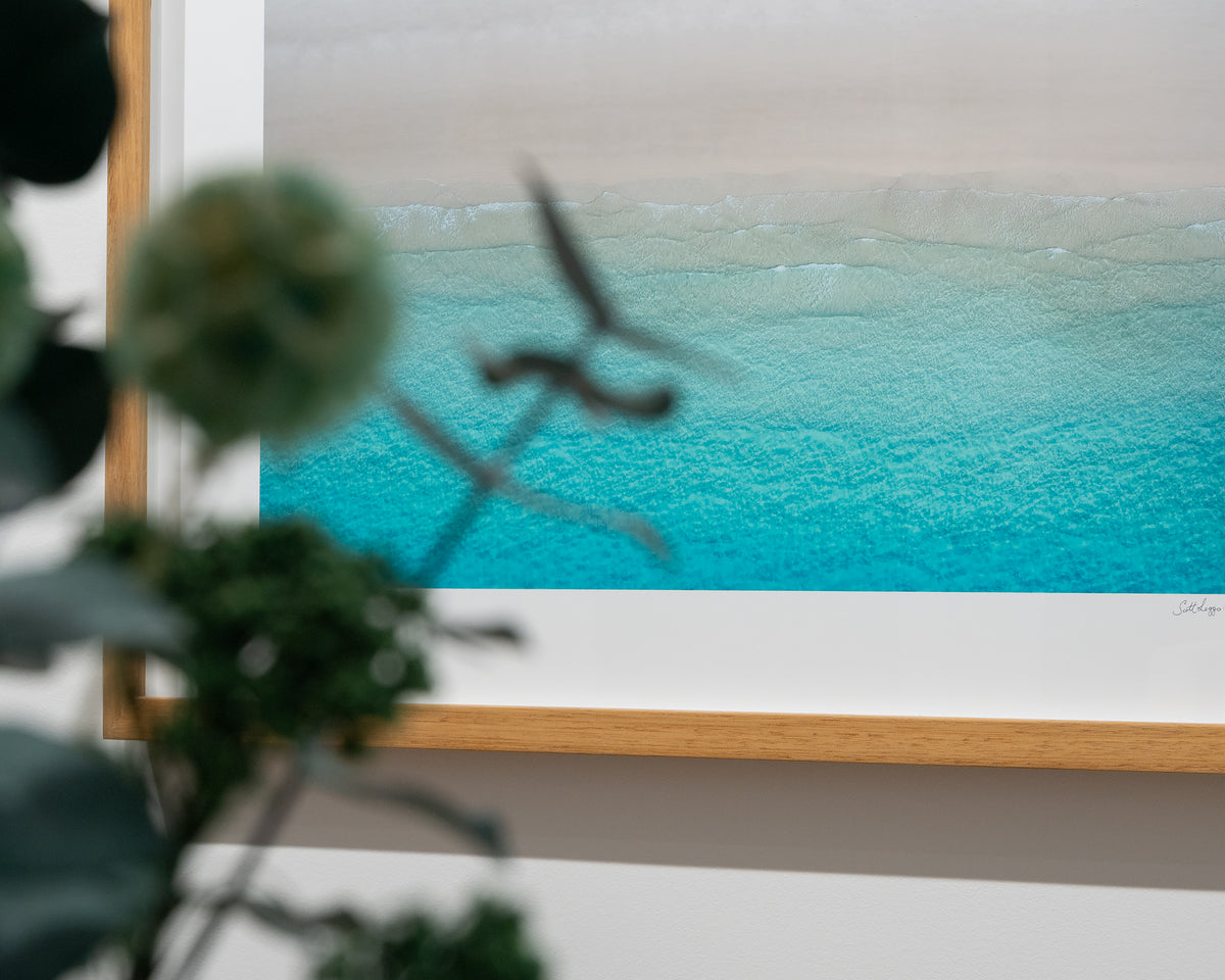 Sea Change. Aerial view Whitehaven Beach, Queensland, with timber frame, lower close up with flower arrangement in foreground.
