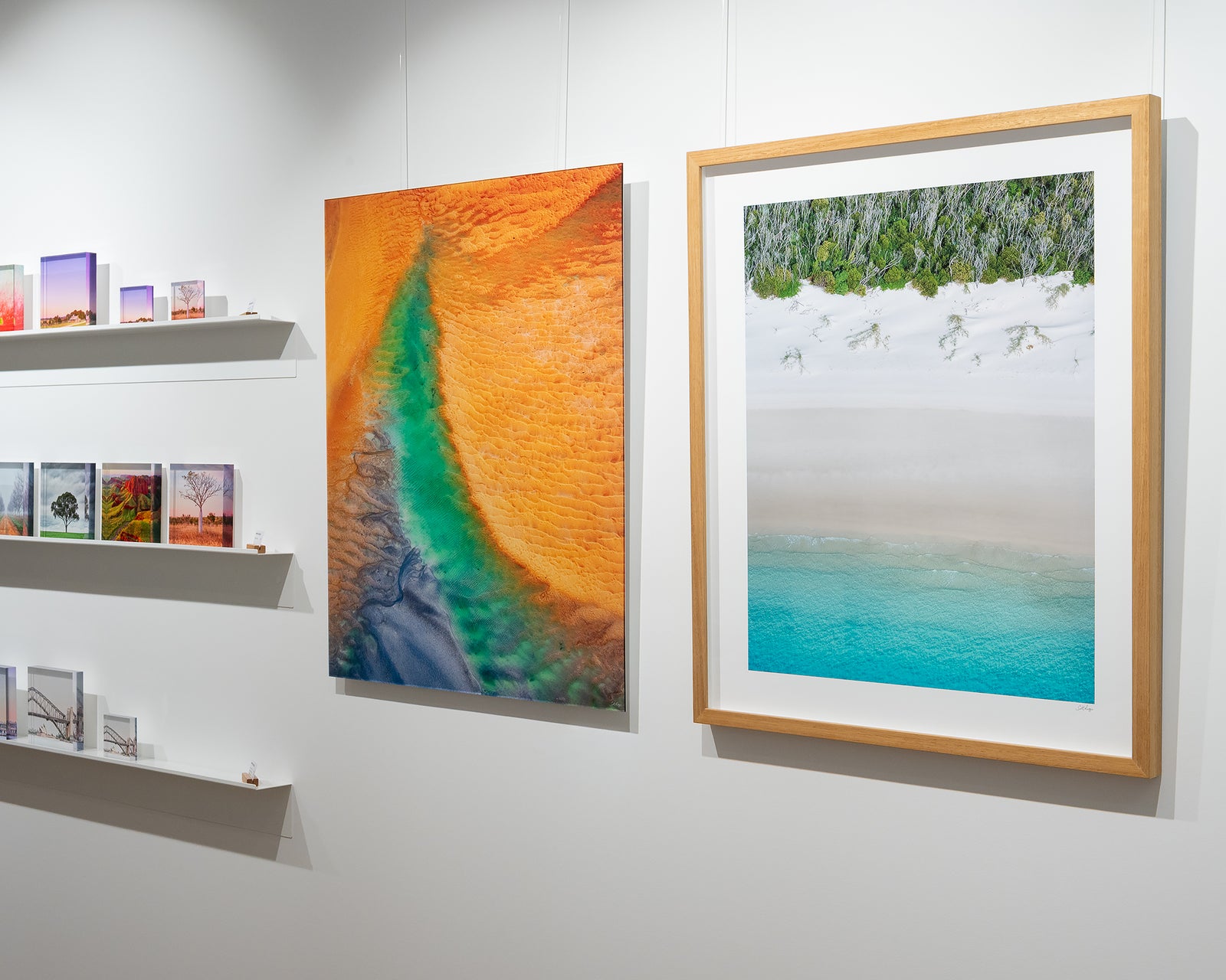 Framed abstract artwork of a beach landscape with turquoise water, white sand and greenery.