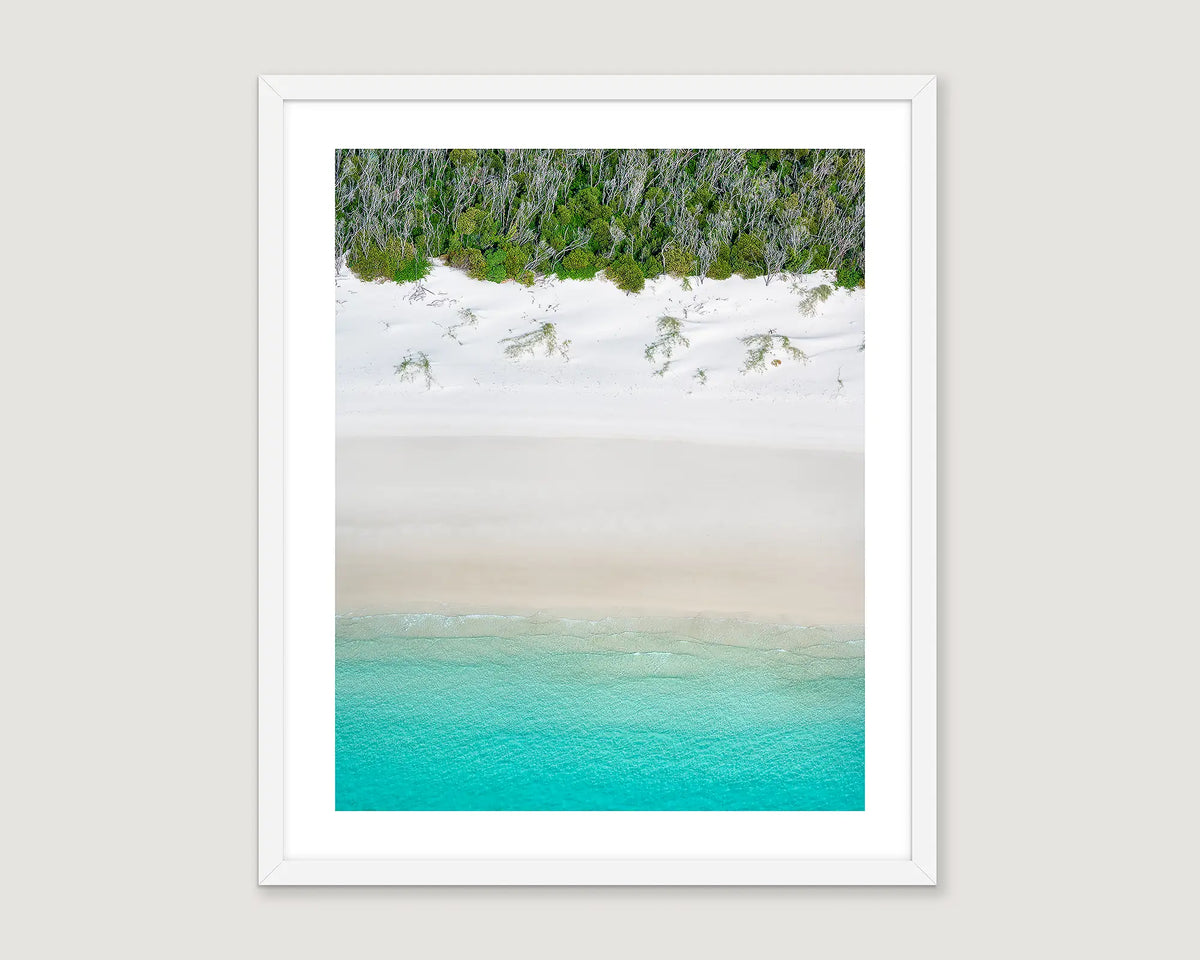 Framed abstract artwork of a beach landscape with turquoise water, white sand and greenery.