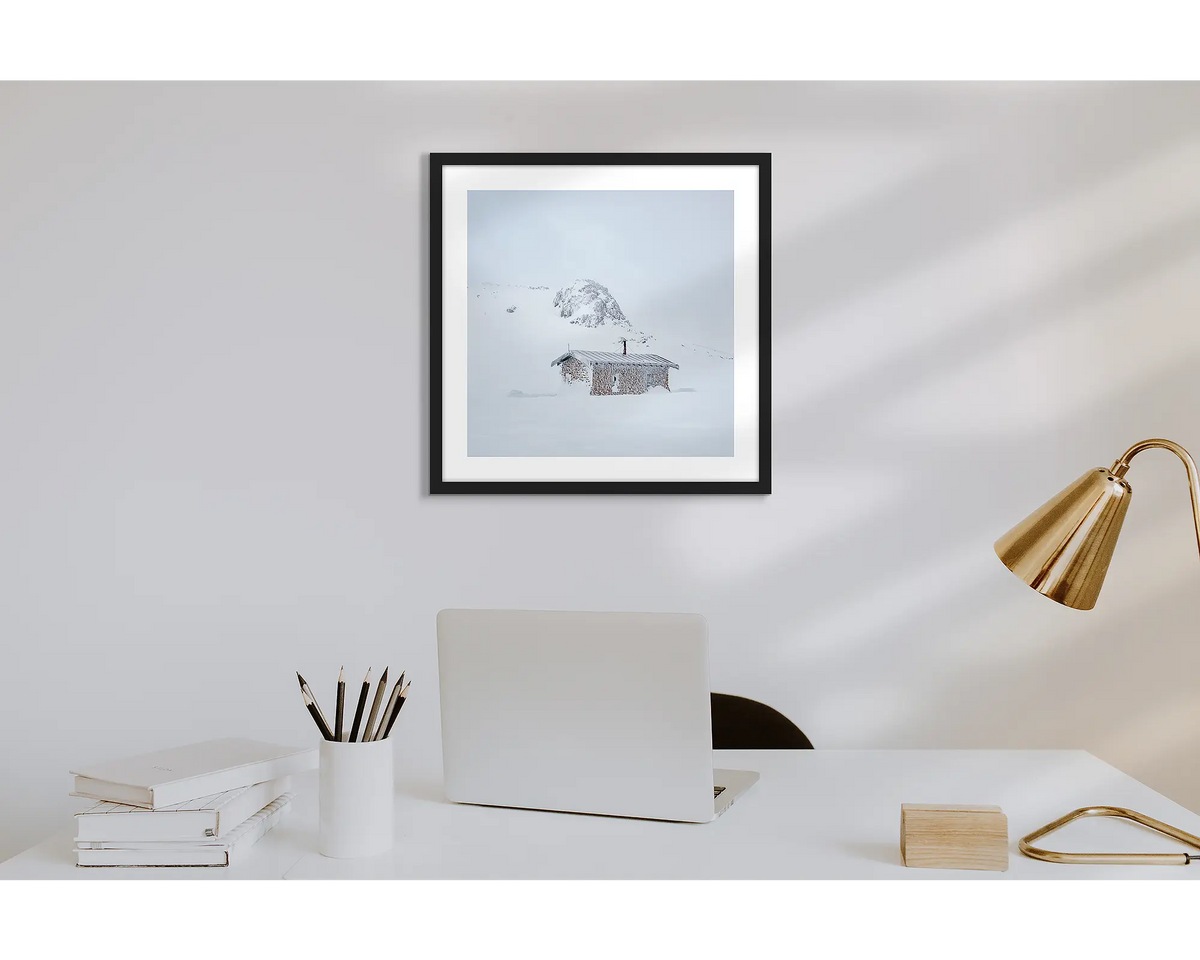 Seaman&#39;s Hut. Wall art print of Seaman&#39;s Hut covered in snow and ice, with a black frame in a work from home office.  