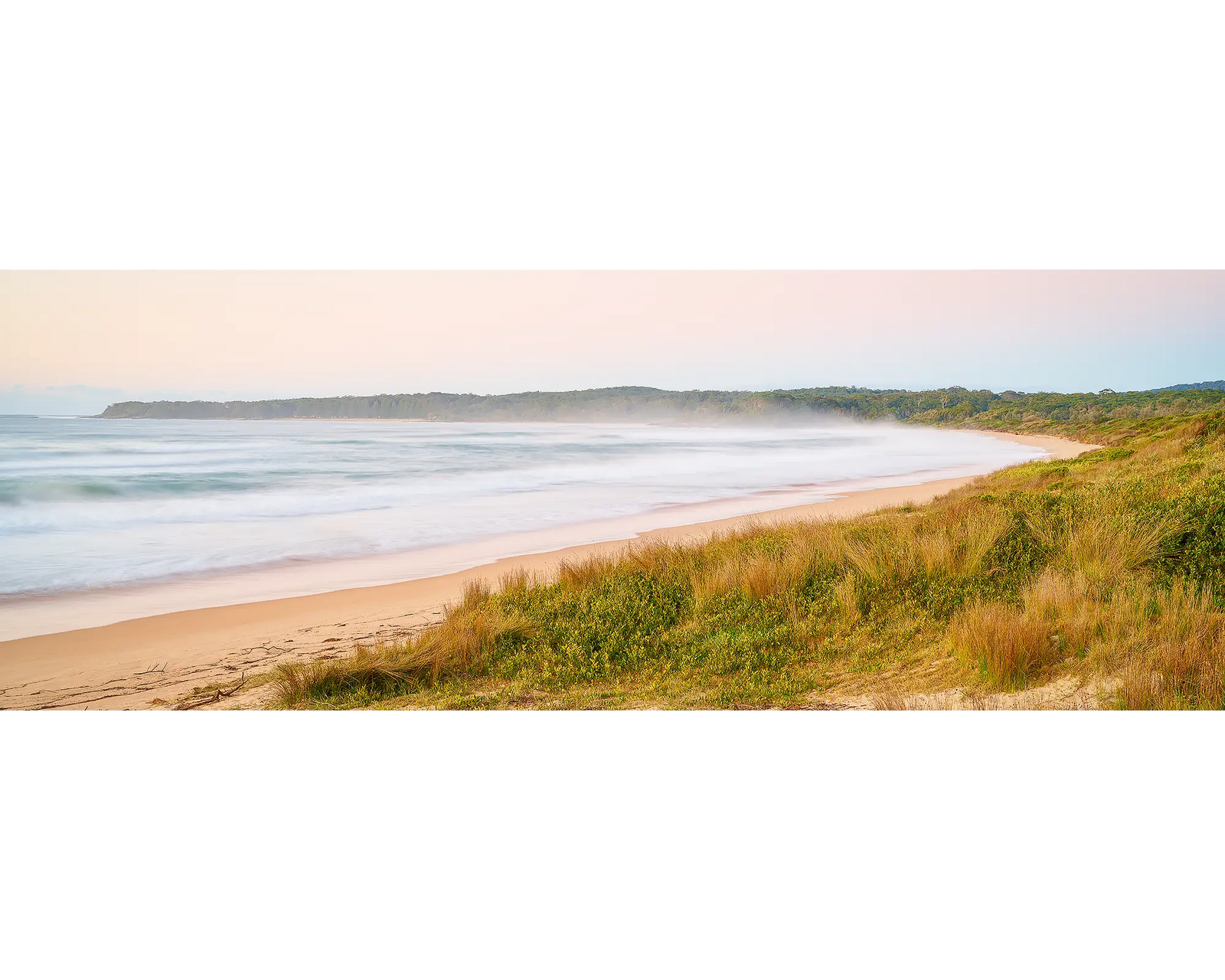 Seaside Dawn. Sunrise beach scene with sand, grass, and water under a clear sky