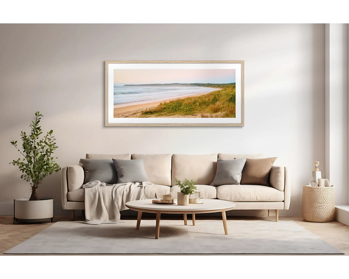 Seaside Dawn. Wall art print of a sunrise at Durras Beach, with a timber frame, hung above a lounge room couch. 