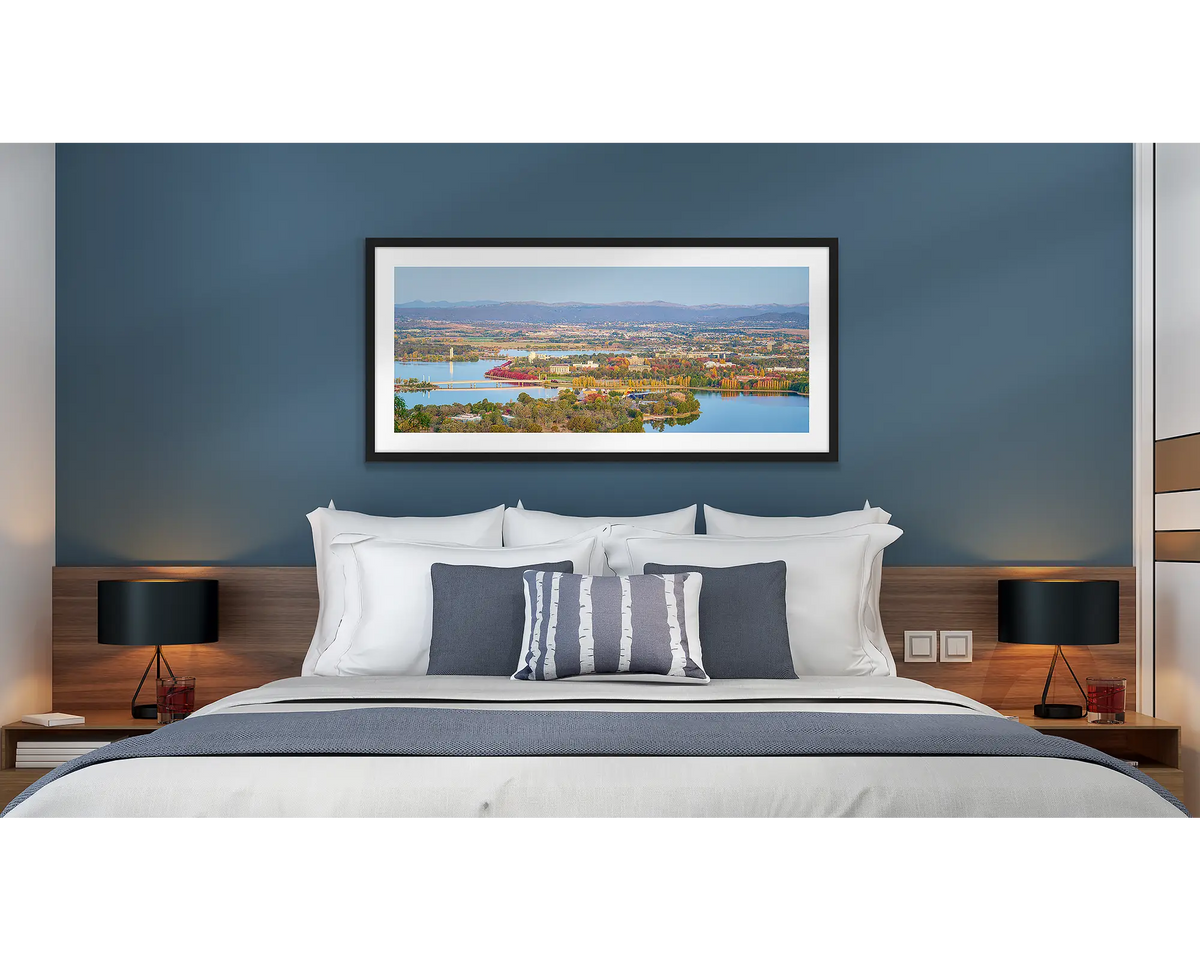 Seasonal Views. Wall art print of an Autumn sunset over Canberra, framed with a black frame and hung above a bed in a hotel room. 