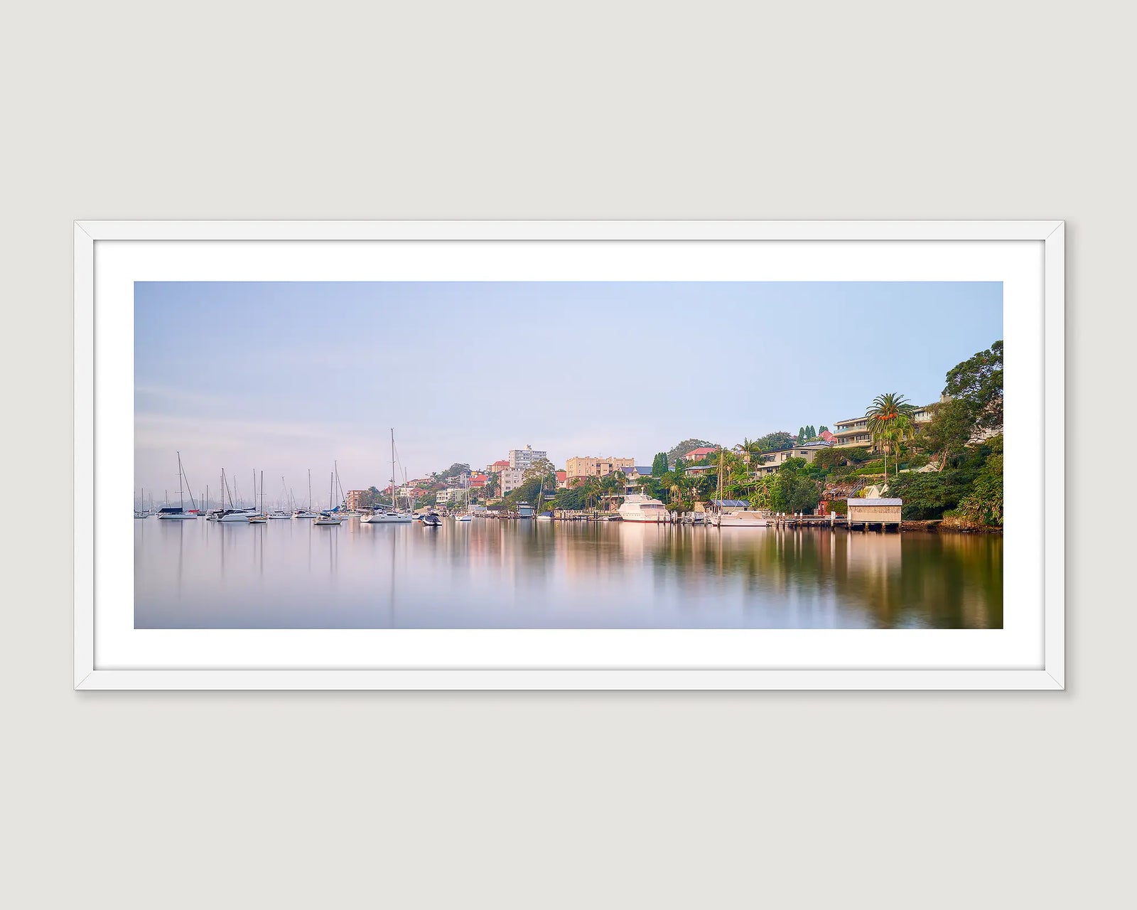 Framed photograph of a Shell Cove waterfront scene with boats and buildings on a grey wall.
