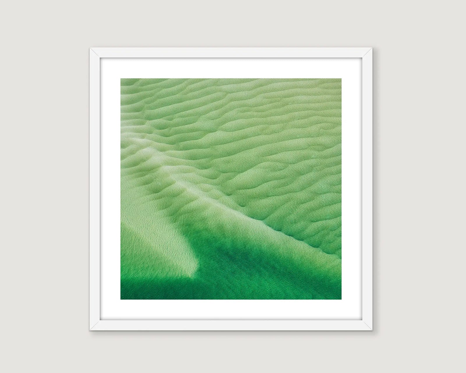 Framed artwork of green abstract water pattern on a white wall.
