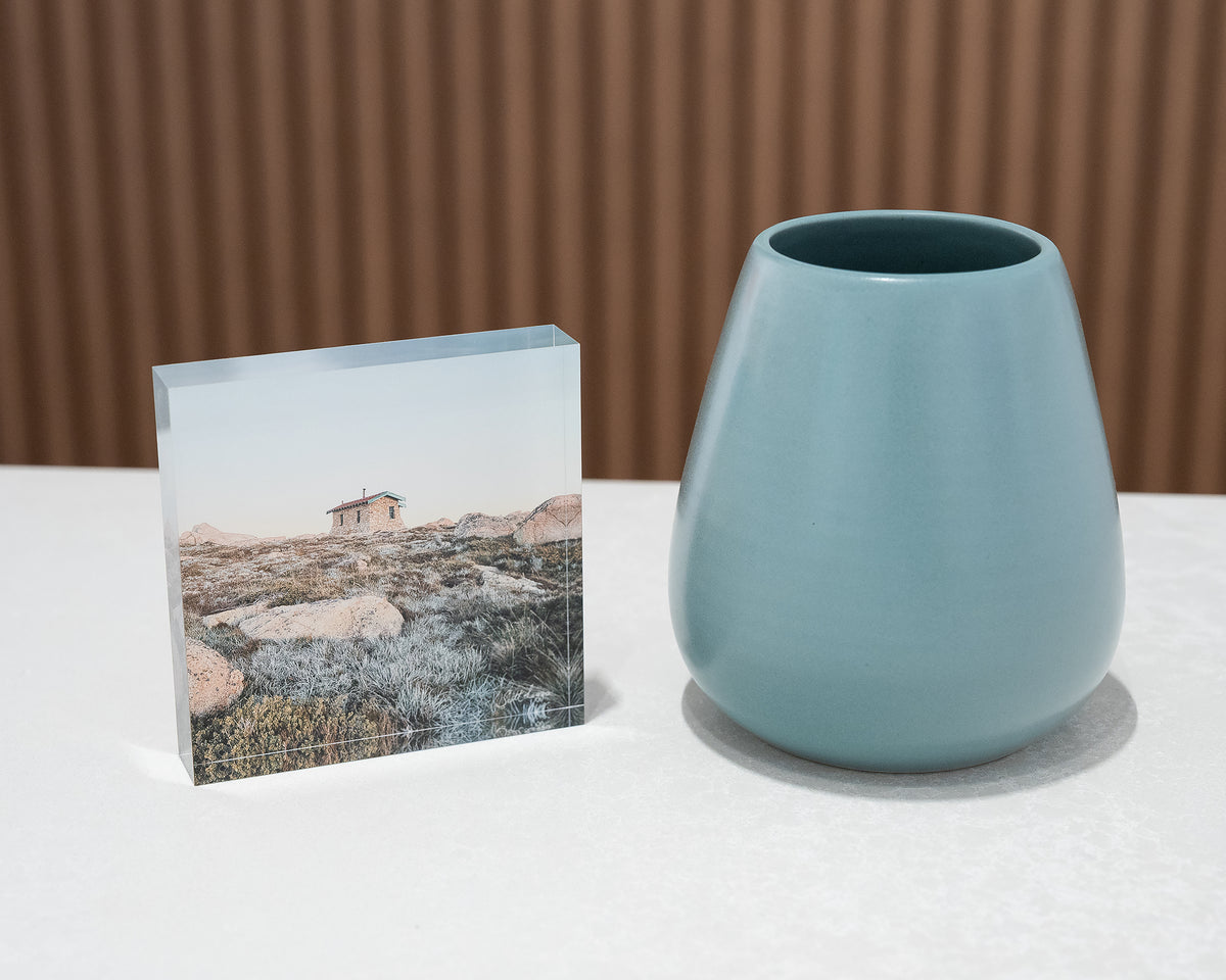 Shelter. Acrylic block Seamans Hut Kosciuszko National Park, New South Wales, on desk styled with small vase.