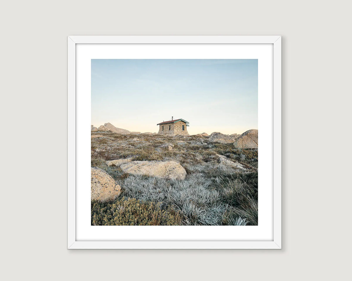 Framed photograph of Seaman's Hut on a rocky landscape with a clear sky.