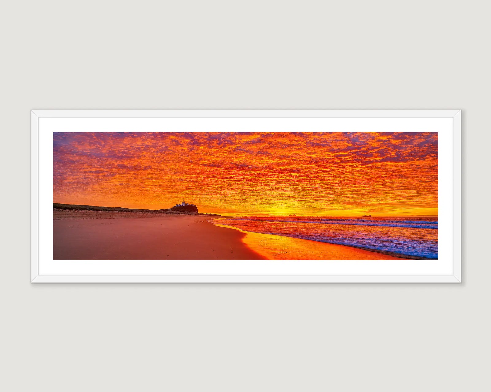 Framed artwork of Nobbys Beach with a vibrant orange and purple coloured sunrise.
