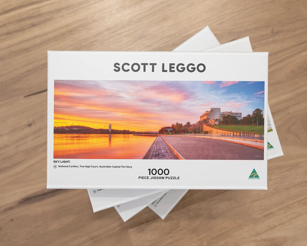 Sky Light. 1000 piece jigsaw puzzle of Autumn sunrise over Canberra, stacked on top of jigsaw puzzles.