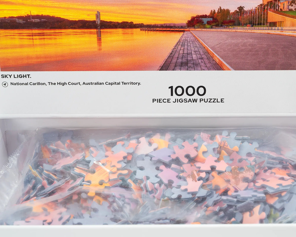 Sky Light. 1000 piece jigsaw puzzle of Autumn sunrise over Lake Burley Griffin, open box showing puzzle pieces.