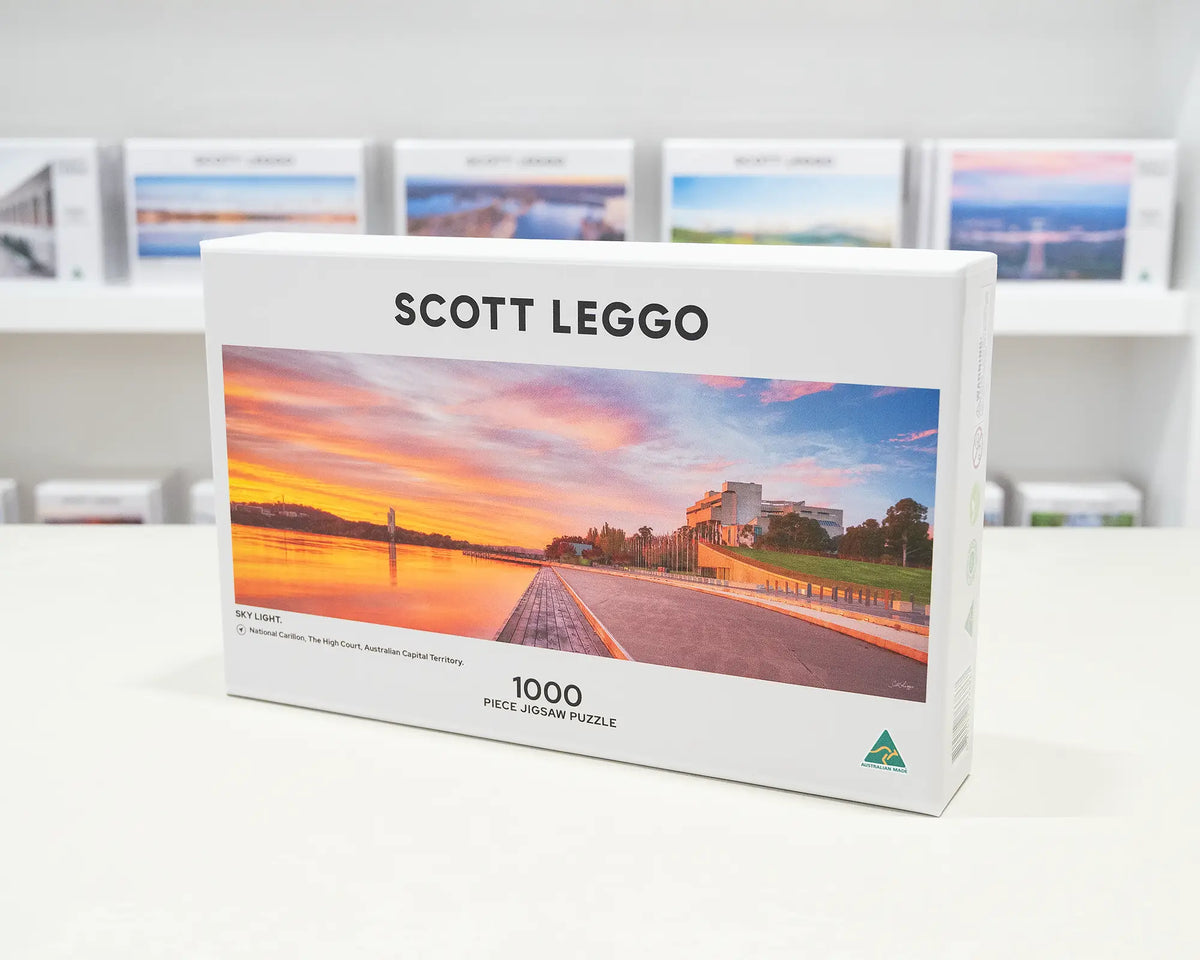 Sky Light. 1000 piece jigsaw puzzle of Autumn sunrise over Lake Burley Griffin, sitting on a desk in the gallery.