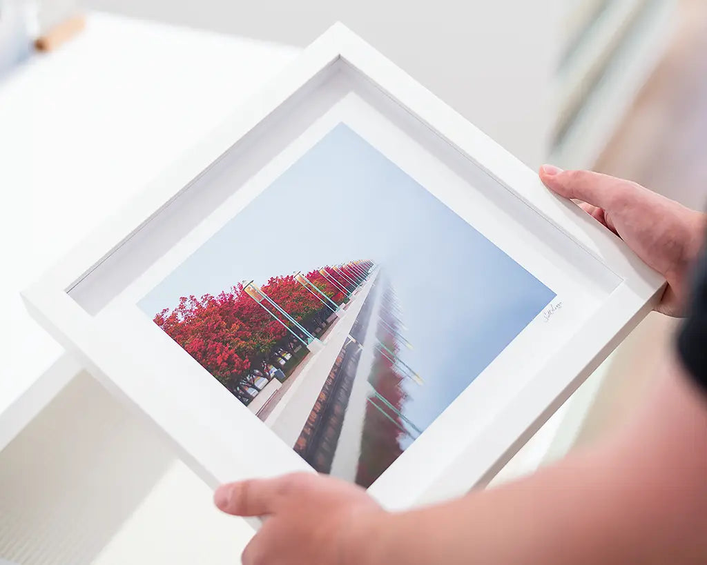Small framed print with white frame being held.