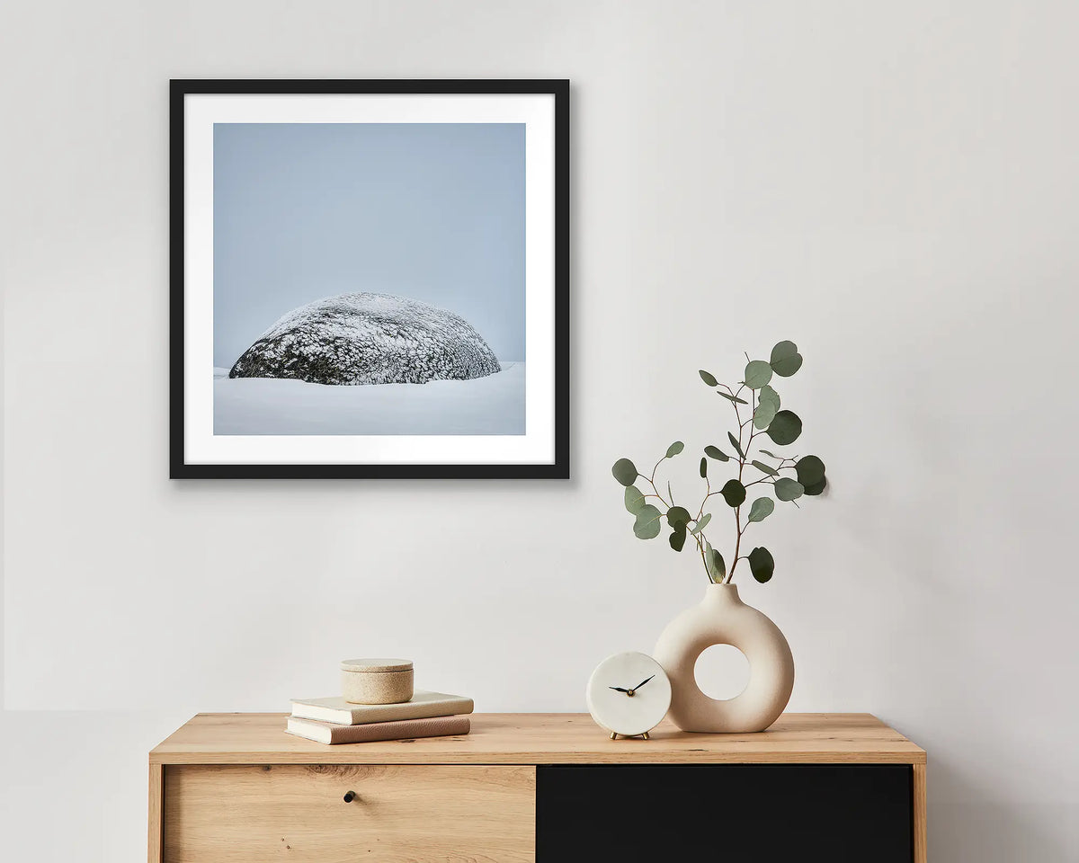 Snow Dome. Framed wall art print of a rock covered in ice with a black frame, hung above a small entrance table.