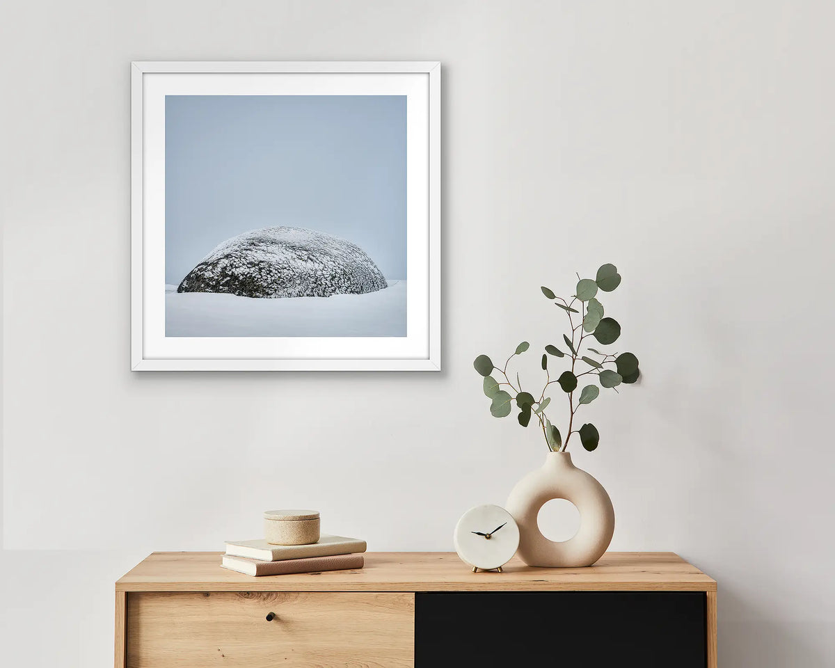 Snow Dome. Framed wall art print of a rock covered in ice with a white frame, hung above a small entrance table.