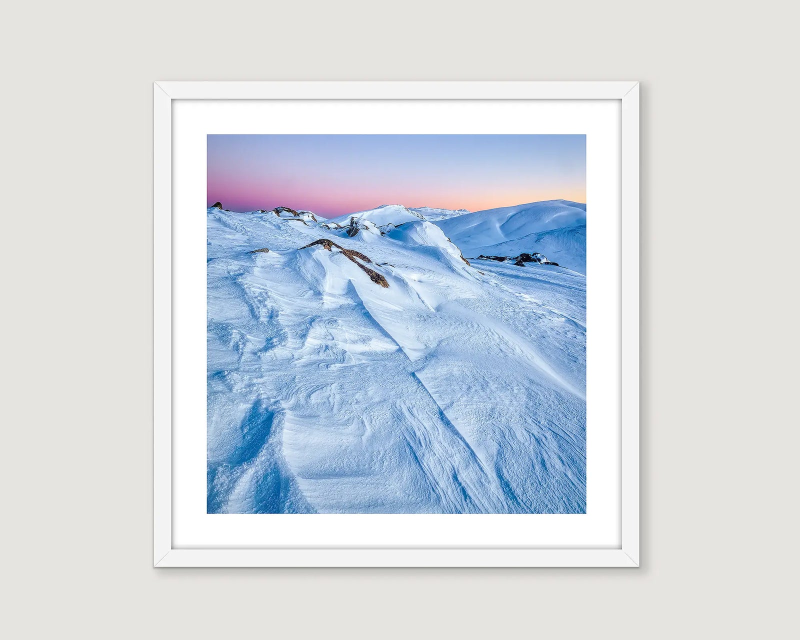 Framed photograph of snow covered mountains and a colourful sunrise and clear sky.
