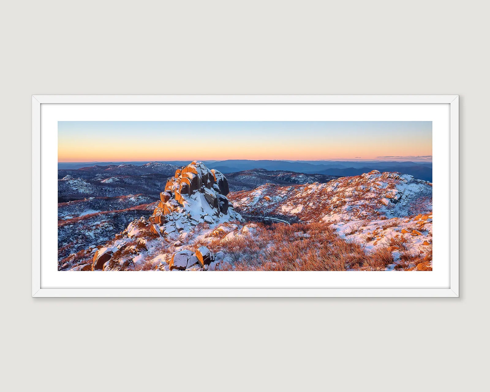 Framed panoramic landscape of a snowy Cathedral mountain peak with a sunset sky.