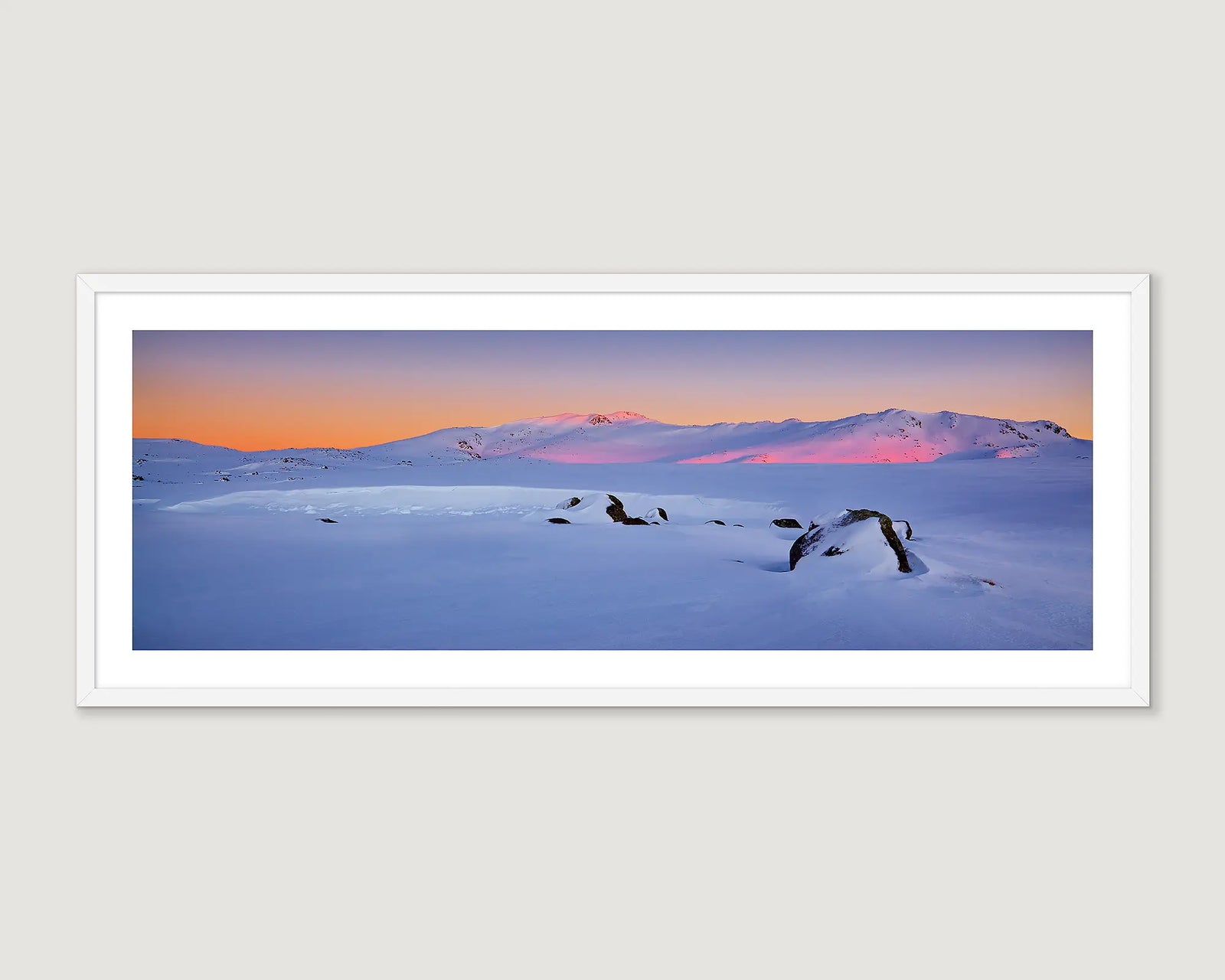 Framed photograph of a snowy landscape with mountains and a colourful sky.