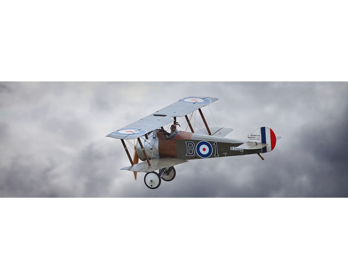 Sopwith Camel flying against backdrop of clouds.