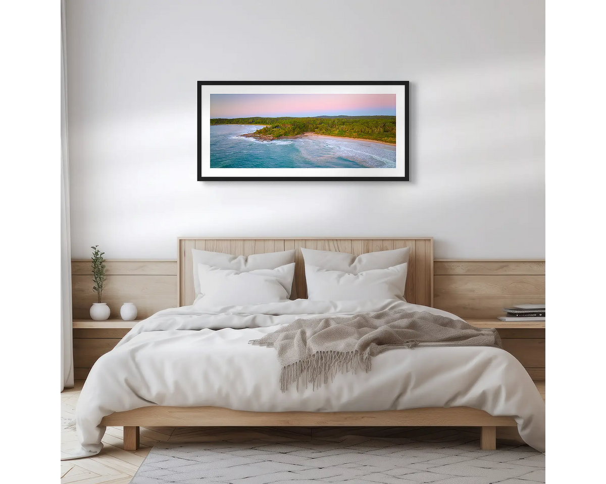 South Coast Escape. Wall art print of a sunrise over Durras, with a black frame hung above a bed. 