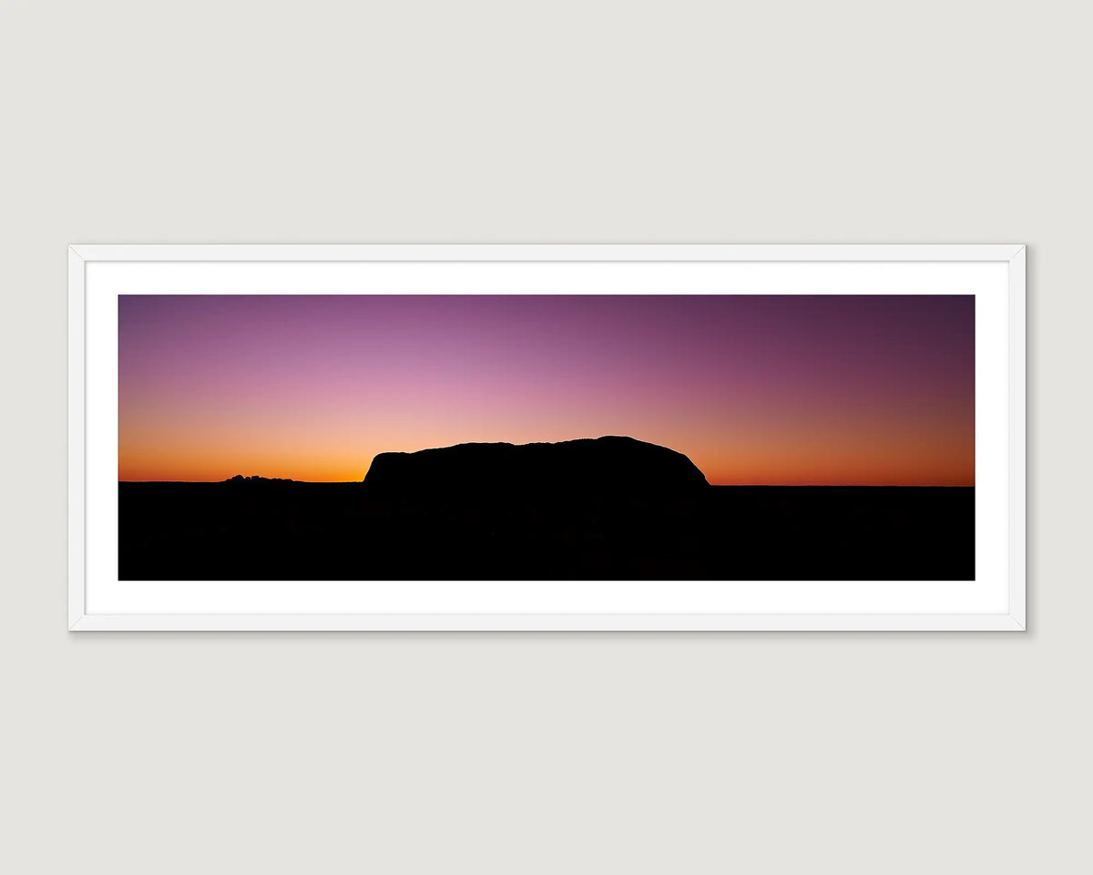 Framed artwork of a silhouette of the Uluru rock against a colourful sunset sky.